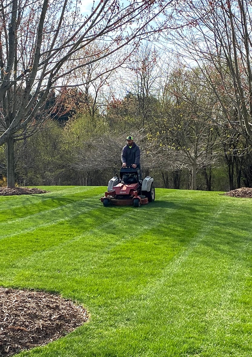 Landscaper mowing grass at a residential lot.