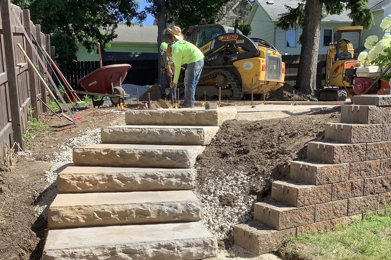 Lanscape team installing stone paver stairs.