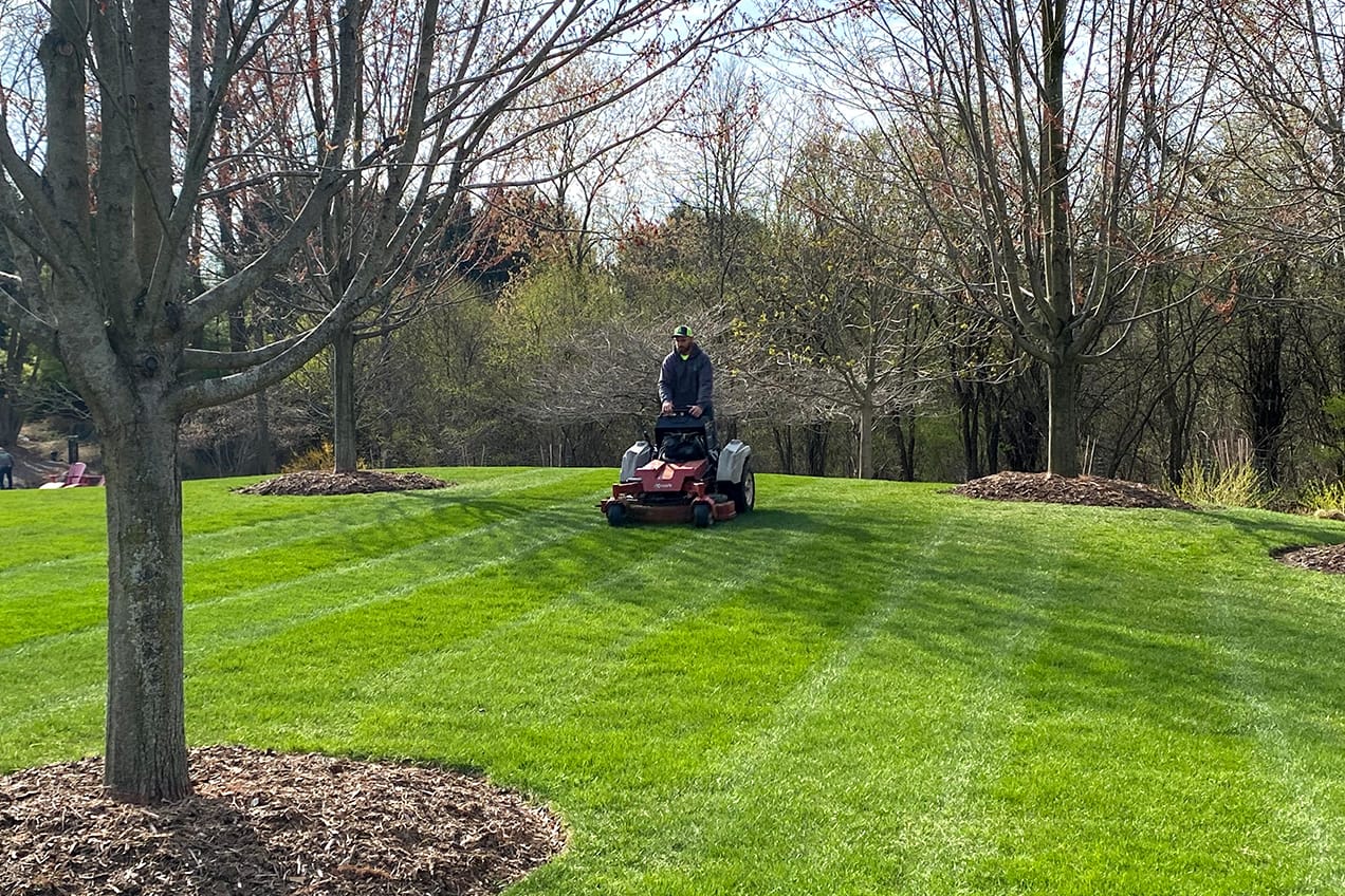 Lanscaper mowing grass.